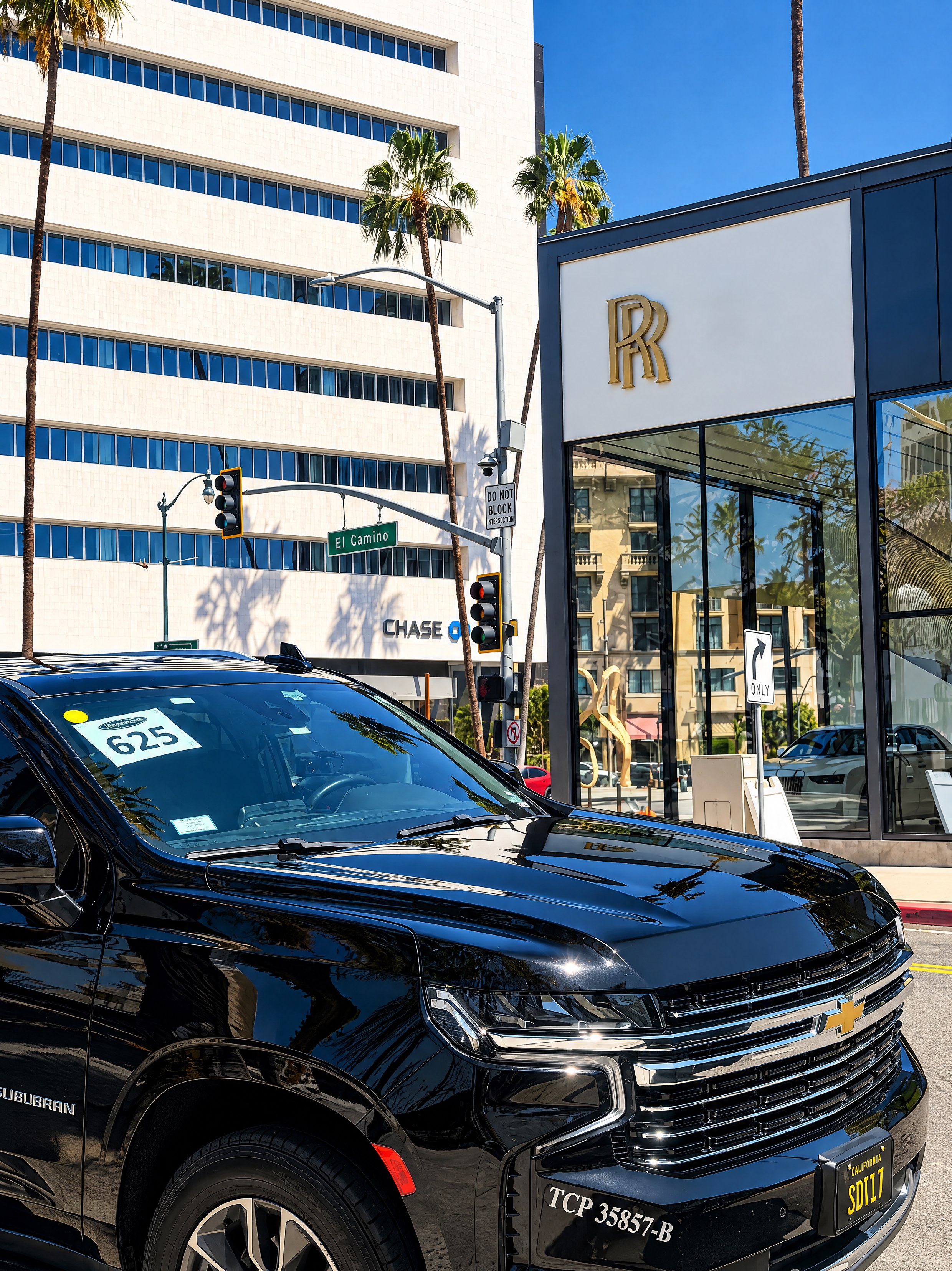Pacific Elite Rides black Chevrolet Suburban credentialed for limo service, parked in Beverly Hills near the Rolls-Royce dealership